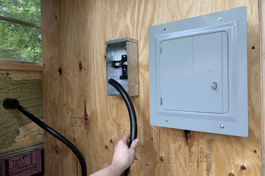 a hand holding the recently installed 50 amp wire from the power inlet